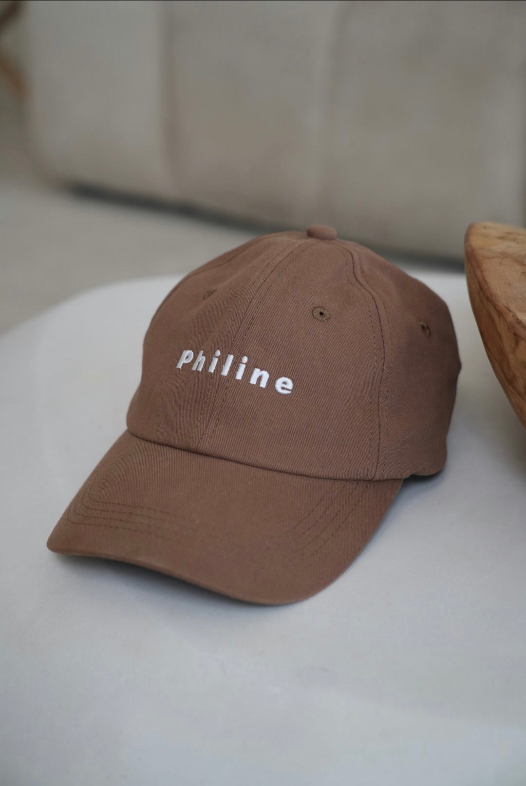 Brown cap with 'philine' text on a white surface