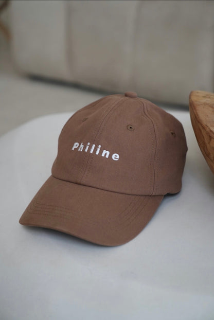 Brown cap with 'philine' text on a white surface