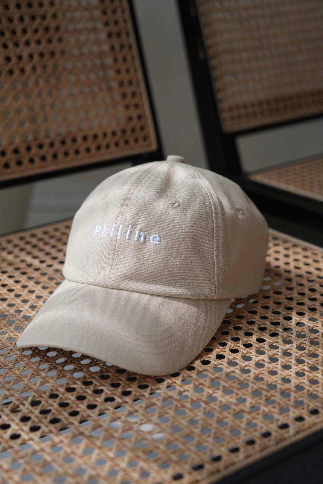Beige cap with 'Philine' embroidery on a woven surface