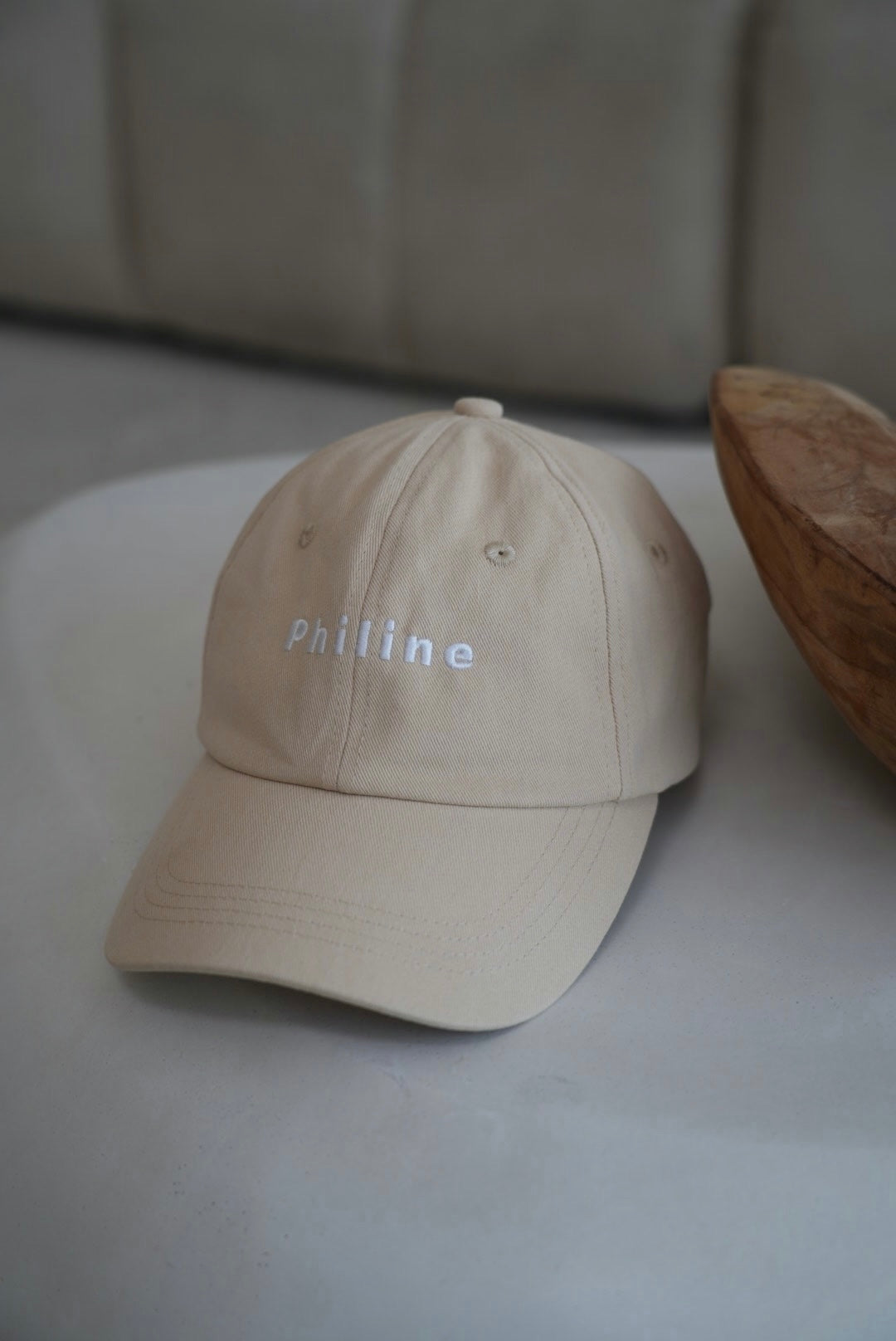 Beige cap with 'Philine' branding on a light surface