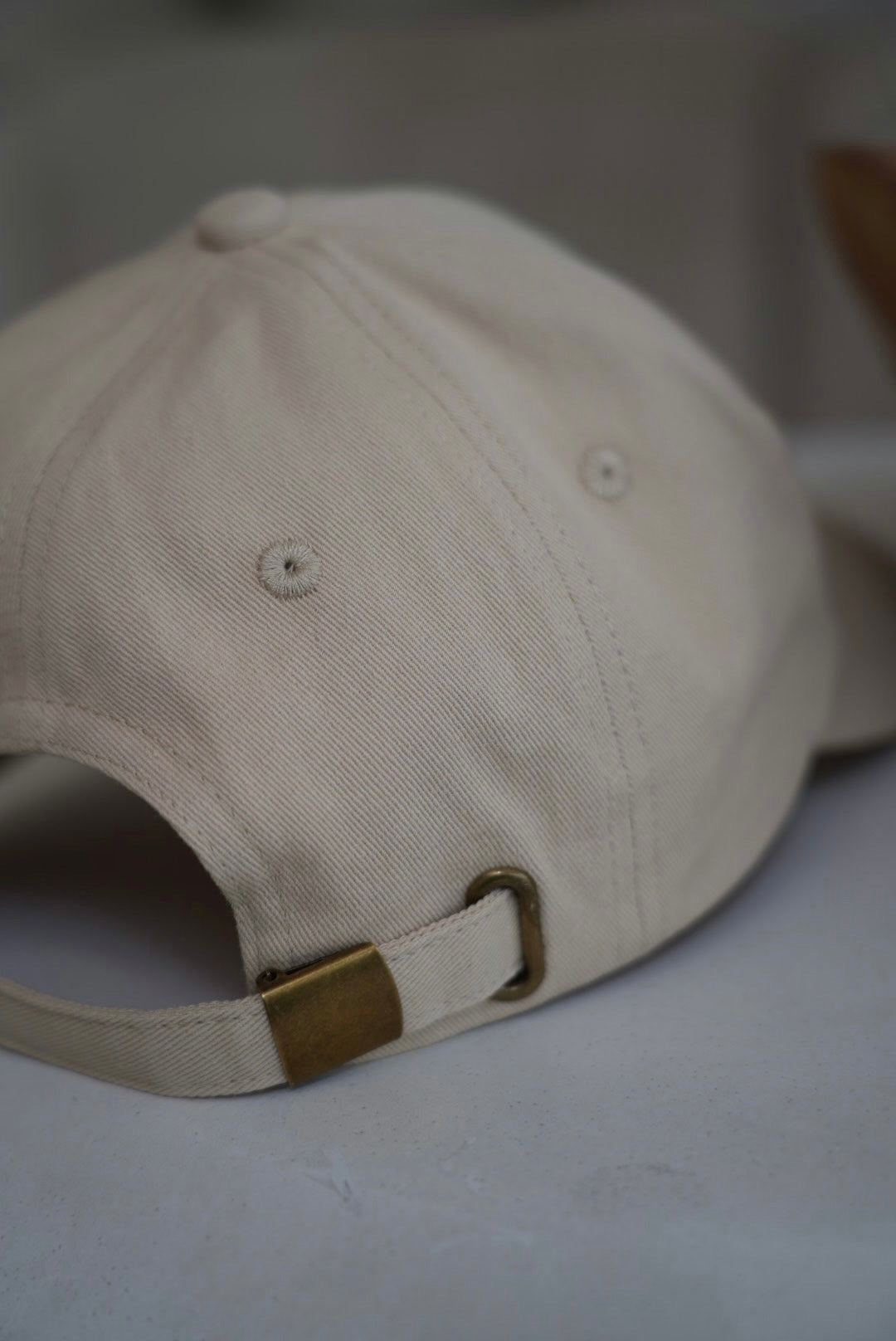 Beige baseball cap with a brown buckle on a light background