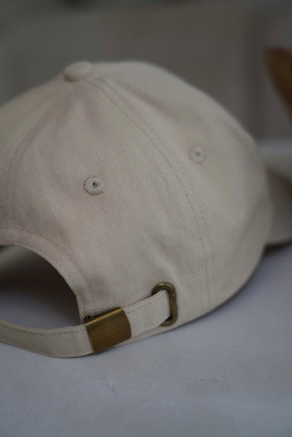 Beige baseball cap with a brown buckle on a light background