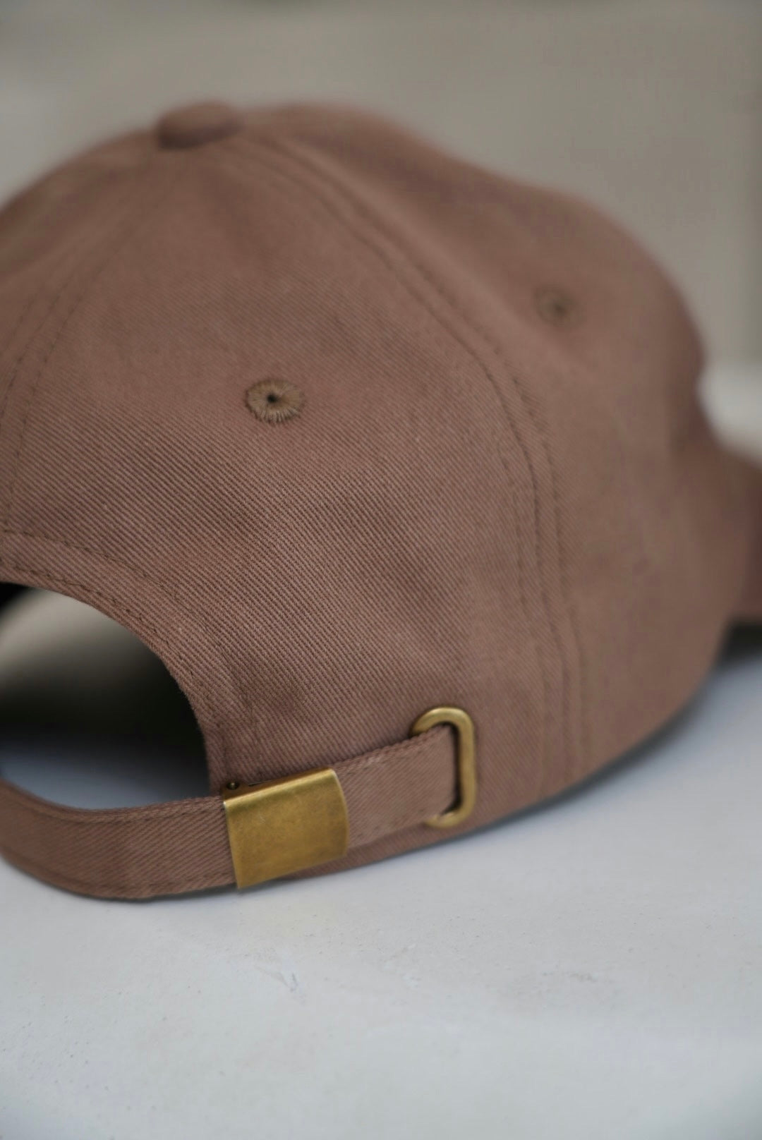 Brown cap with a gold buckle on a light gray background